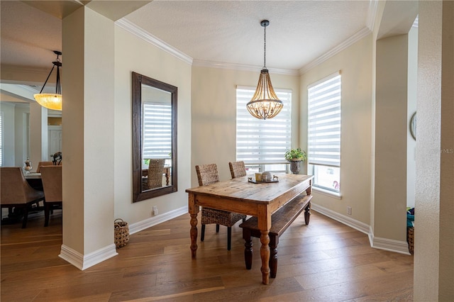 dining area featuring a chandelier, wood-type flooring, baseboards, and crown molding