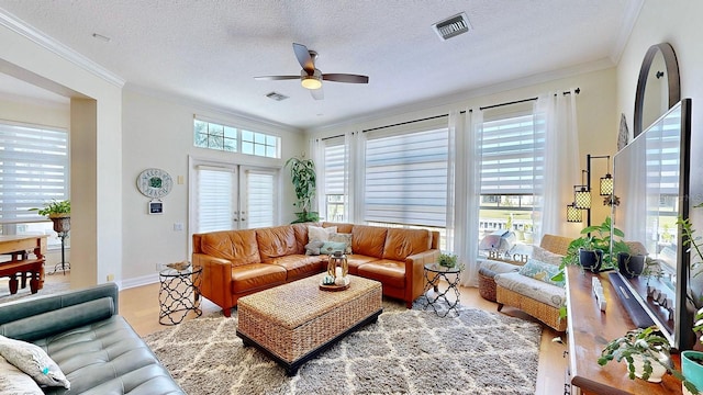 living room with a textured ceiling, visible vents, and crown molding