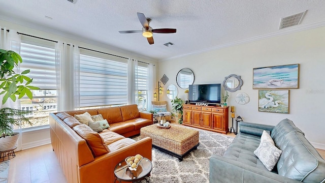 living area with a ceiling fan, visible vents, crown molding, and light wood finished floors