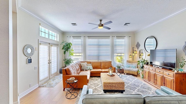 living area with ornamental molding, french doors, a healthy amount of sunlight, and light wood-style flooring