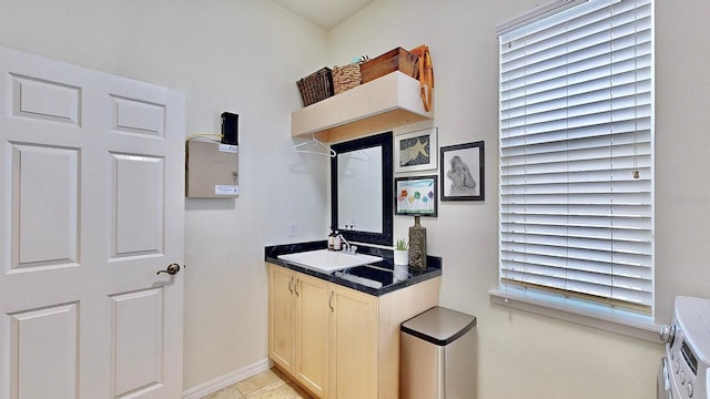 interior space featuring dark countertops, a sink, washer / dryer, and baseboards