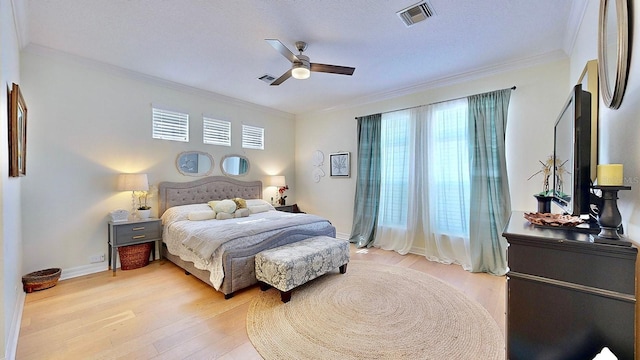 bedroom featuring light wood-style floors, multiple windows, visible vents, and crown molding