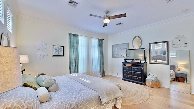 bedroom featuring ornamental molding, wood finished floors, visible vents, and baseboards