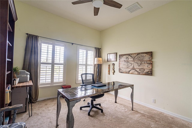 office space with a ceiling fan, visible vents, light carpet, and baseboards