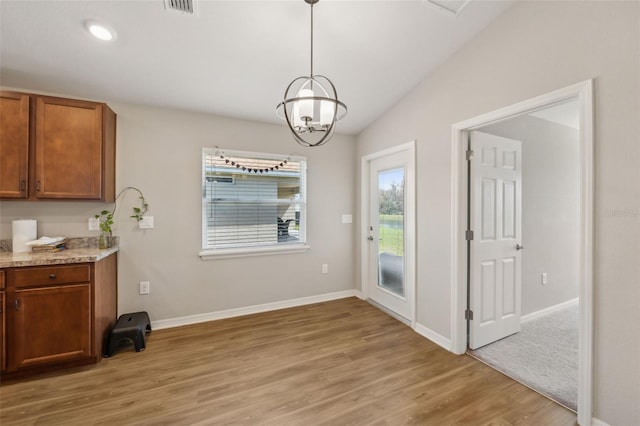 unfurnished dining area with visible vents, baseboards, vaulted ceiling, light wood-type flooring, and an inviting chandelier