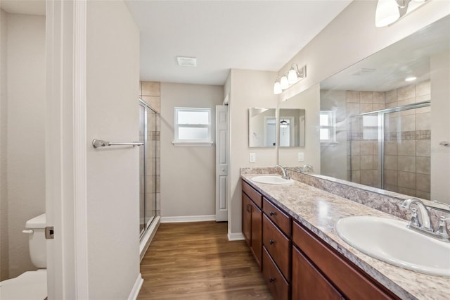 full bath featuring toilet, a stall shower, a sink, and wood finished floors