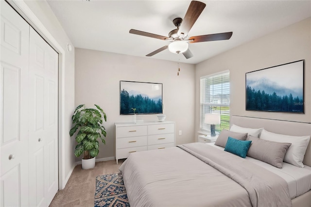 bedroom featuring a closet, light colored carpet, ceiling fan, and baseboards