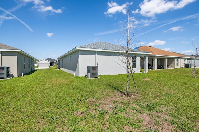 back of property with a yard, central AC unit, and stucco siding