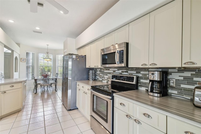 kitchen with light tile patterned floors, stainless steel appliances, visible vents, hanging light fixtures, and tasteful backsplash