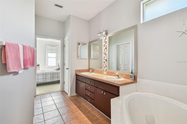 bathroom with double vanity, visible vents, connected bathroom, a sink, and a bath