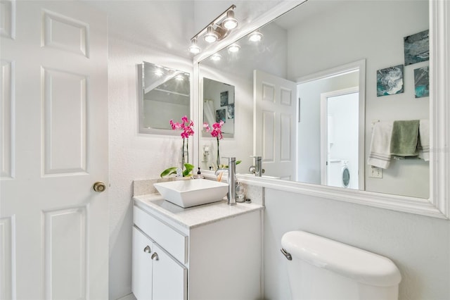 bathroom with toilet, washer / clothes dryer, and vanity