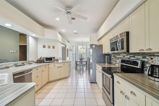 kitchen with light tile patterned floors, light countertops, backsplash, appliances with stainless steel finishes, and a ceiling fan