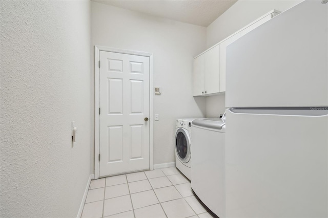 laundry room featuring light tile patterned floors, independent washer and dryer, cabinet space, and baseboards