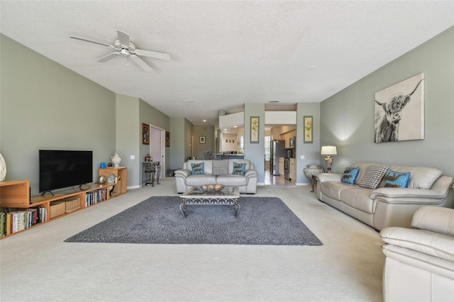 living room with a textured ceiling, carpet floors, a ceiling fan, and baseboards