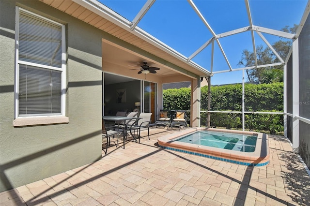 view of swimming pool featuring a patio area, ceiling fan, glass enclosure, and an in ground hot tub