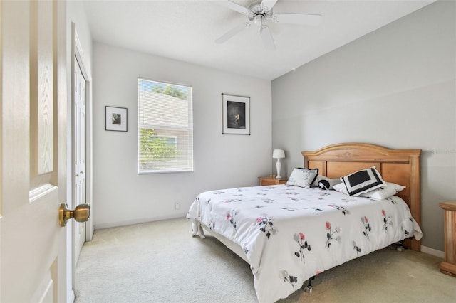 bedroom with a ceiling fan, light carpet, and baseboards