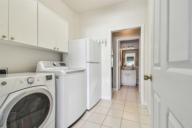 clothes washing area featuring cabinet space, light tile patterned floors, baseboards, and washer and dryer