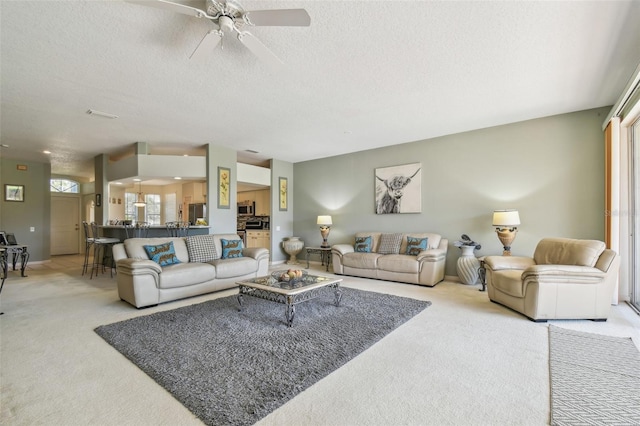 living room featuring ceiling fan, light colored carpet, and a textured ceiling
