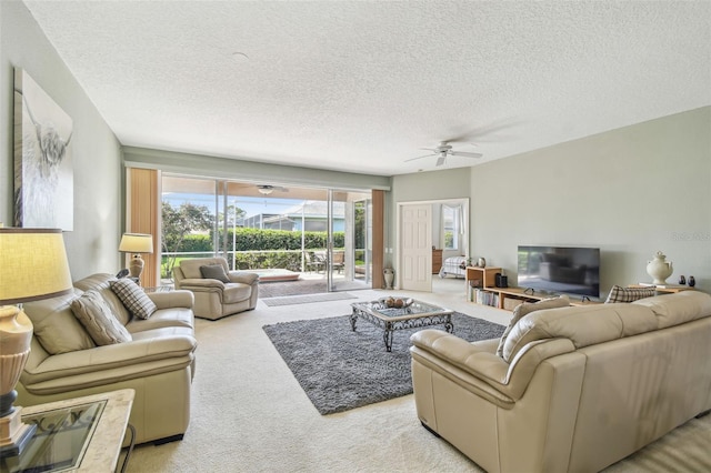 living area with a textured ceiling, ceiling fan, and light colored carpet