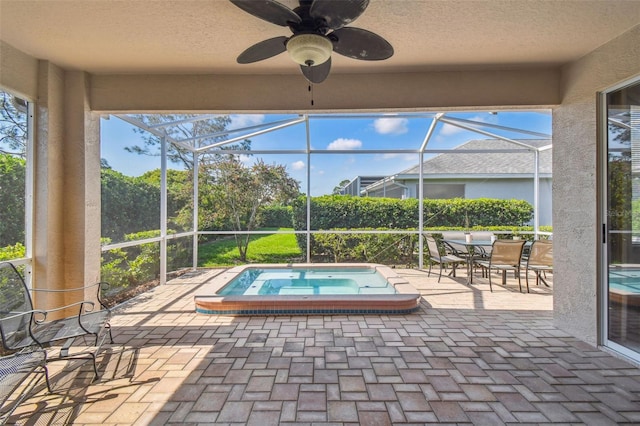 view of patio / terrace with a lanai, a ceiling fan, and an in ground hot tub