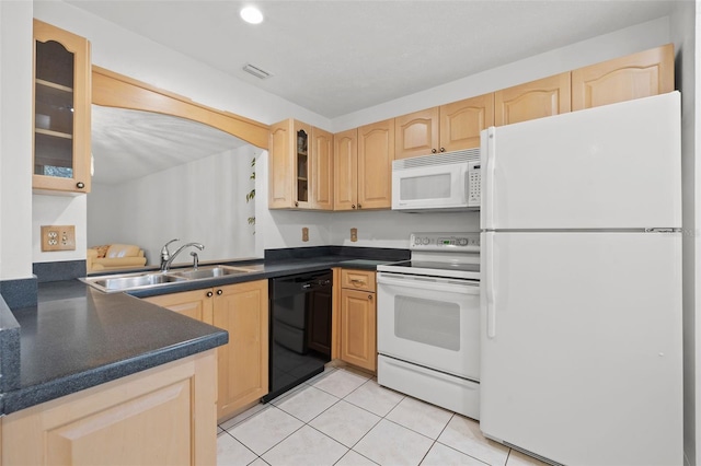 kitchen featuring light brown cabinets, white appliances, dark countertops, and a sink