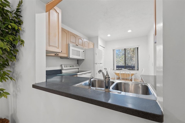 kitchen featuring recessed lighting, white appliances, a sink, light brown cabinetry, and dark countertops