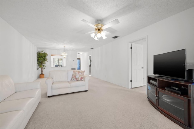 living room with light colored carpet, visible vents, a textured ceiling, and ceiling fan with notable chandelier