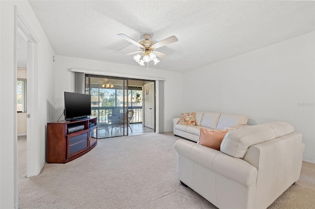 carpeted living room featuring ceiling fan and a textured ceiling