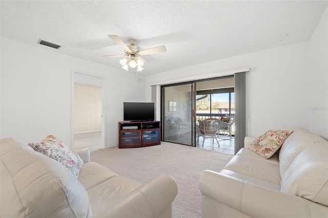 living area with a textured ceiling, ceiling fan, carpet, and visible vents