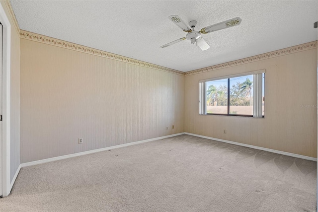 carpeted empty room with a textured ceiling, ceiling fan, and baseboards