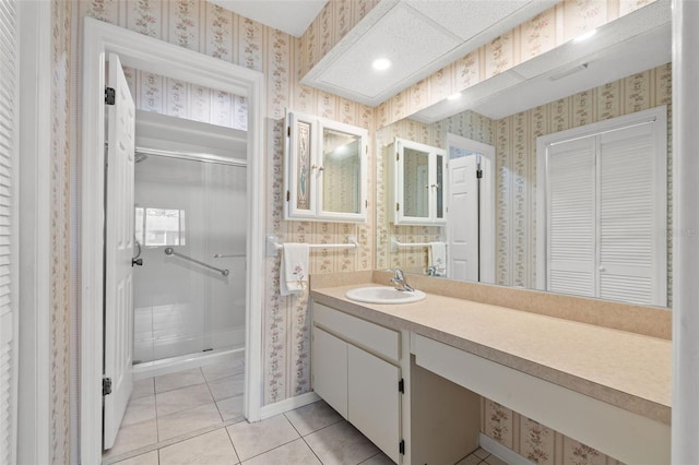 full bathroom with a stall shower, tile patterned floors, vanity, and wallpapered walls