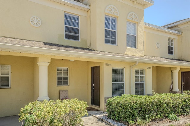 view of front of house with a shingled roof and stucco siding