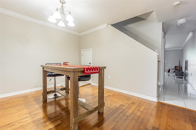 recreation room featuring hardwood / wood-style flooring, baseboards, ornamental molding, and a notable chandelier