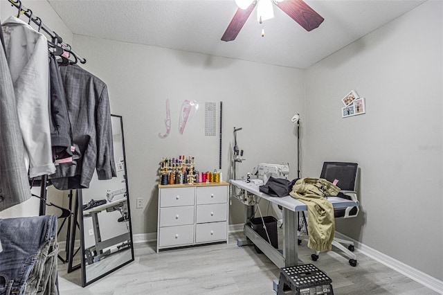 interior space with ceiling fan, light wood finished floors, a textured ceiling, and baseboards