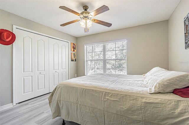 bedroom featuring ceiling fan, a closet, a textured ceiling, and light wood-style floors