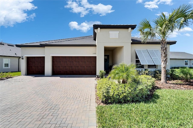 prairie-style home with a garage, a tile roof, decorative driveway, and stucco siding