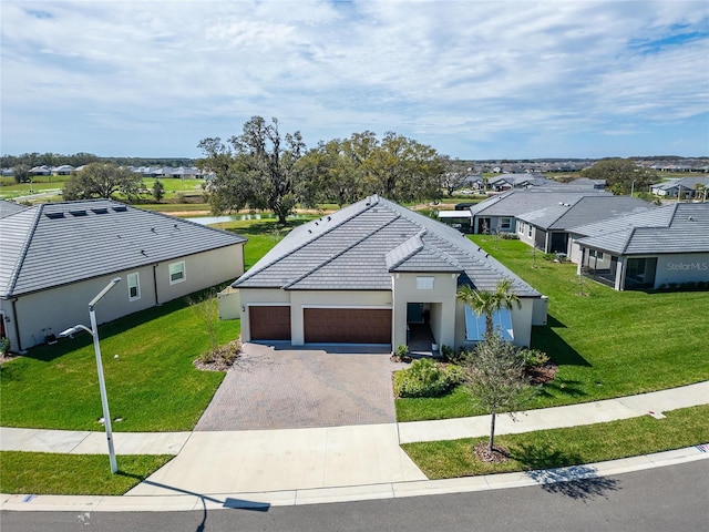 view of front of home featuring a tiled roof, decorative driveway, a front yard, and a residential view