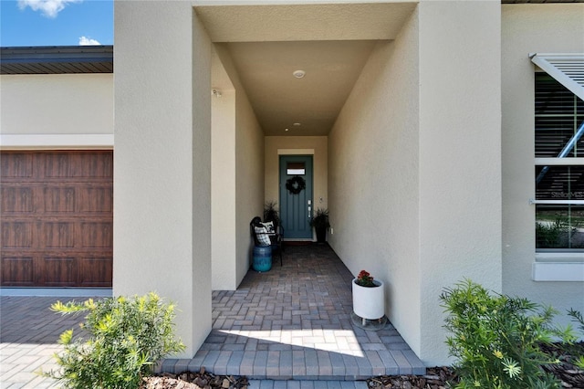 doorway to property with a garage and stucco siding