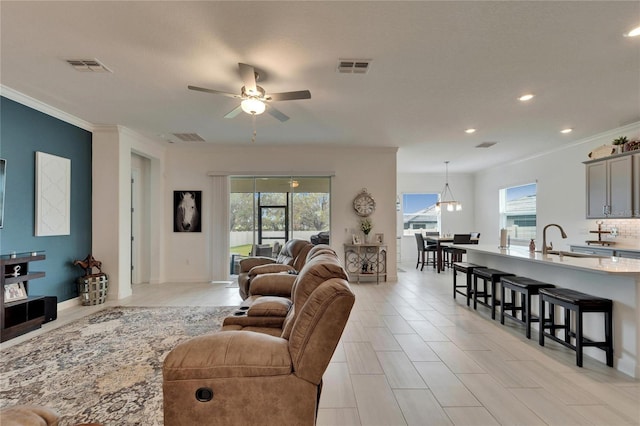 living area with ceiling fan, visible vents, and ornamental molding
