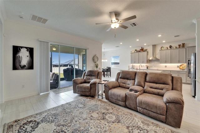 living area with a ceiling fan, visible vents, crown molding, and baseboards