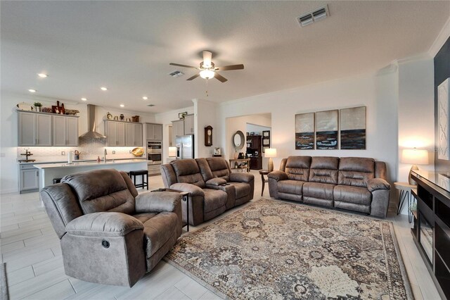 living area with recessed lighting, visible vents, a ceiling fan, and ornamental molding