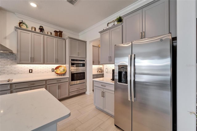 kitchen featuring ornamental molding, stainless steel appliances, decorative backsplash, and gray cabinetry