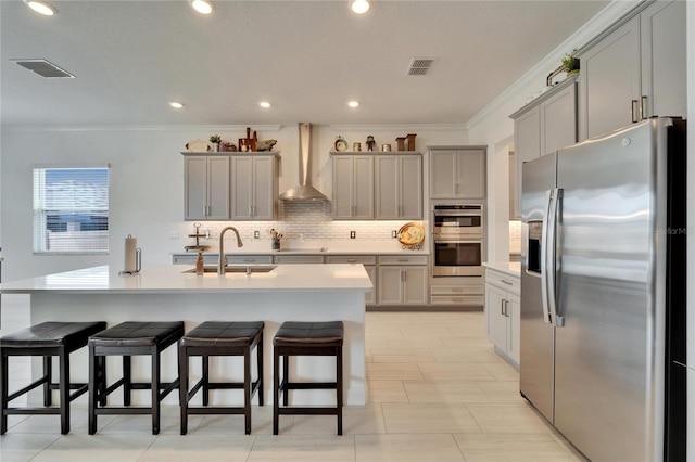 kitchen featuring appliances with stainless steel finishes, gray cabinets, a sink, and wall chimney exhaust hood