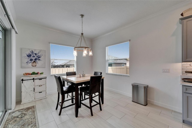 dining room with a chandelier, baseboards, a wealth of natural light, and crown molding
