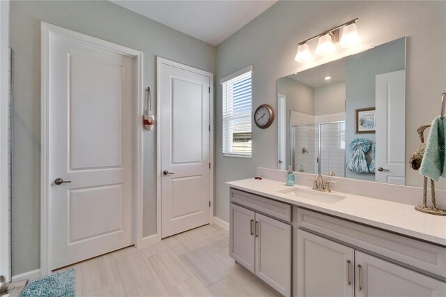 bathroom featuring baseboards, a shower stall, and vanity