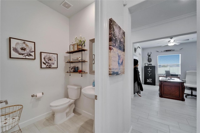 bathroom featuring visible vents, baseboards, toilet, ceiling fan, and crown molding