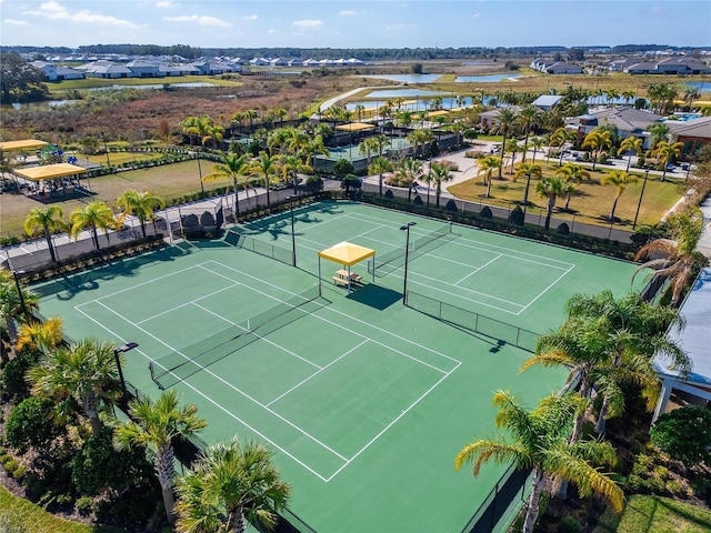 view of tennis court featuring a water view and fence