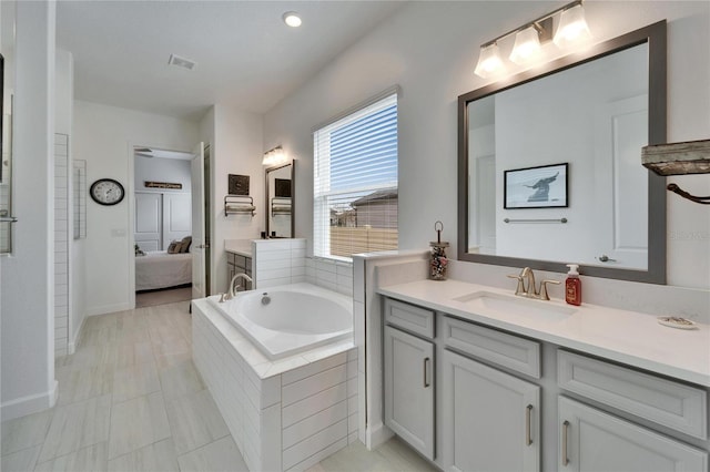 ensuite bathroom with a garden tub, vanity, and ensuite bath