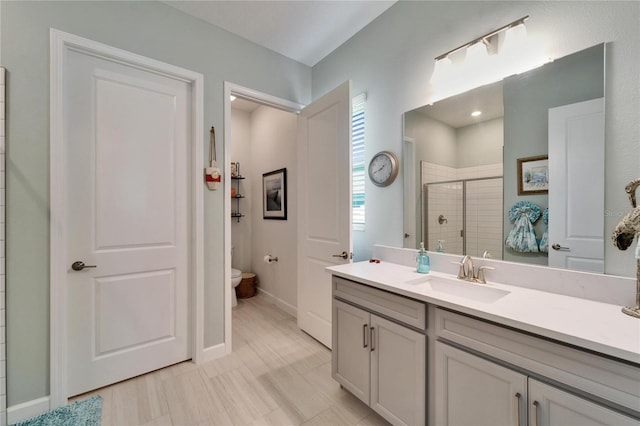 bathroom featuring vanity, a shower stall, toilet, and baseboards