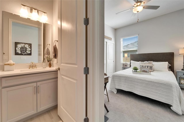 bedroom featuring a ceiling fan, a sink, and ensuite bath